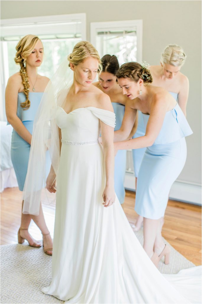 Bride's dress getting zipped by bridesmaids