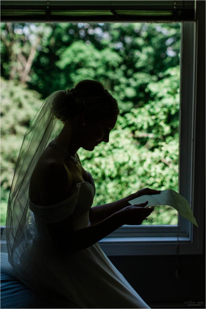Silhouette of bride reading letter in front of window