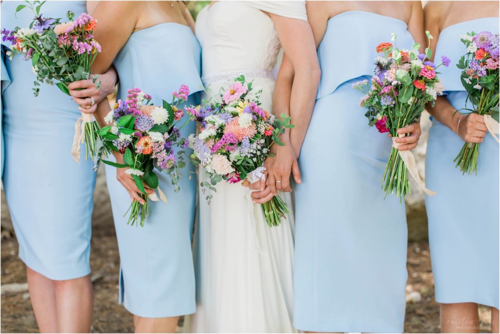 Bride and bridesmaids in blue dresses holding wildflower bouquets