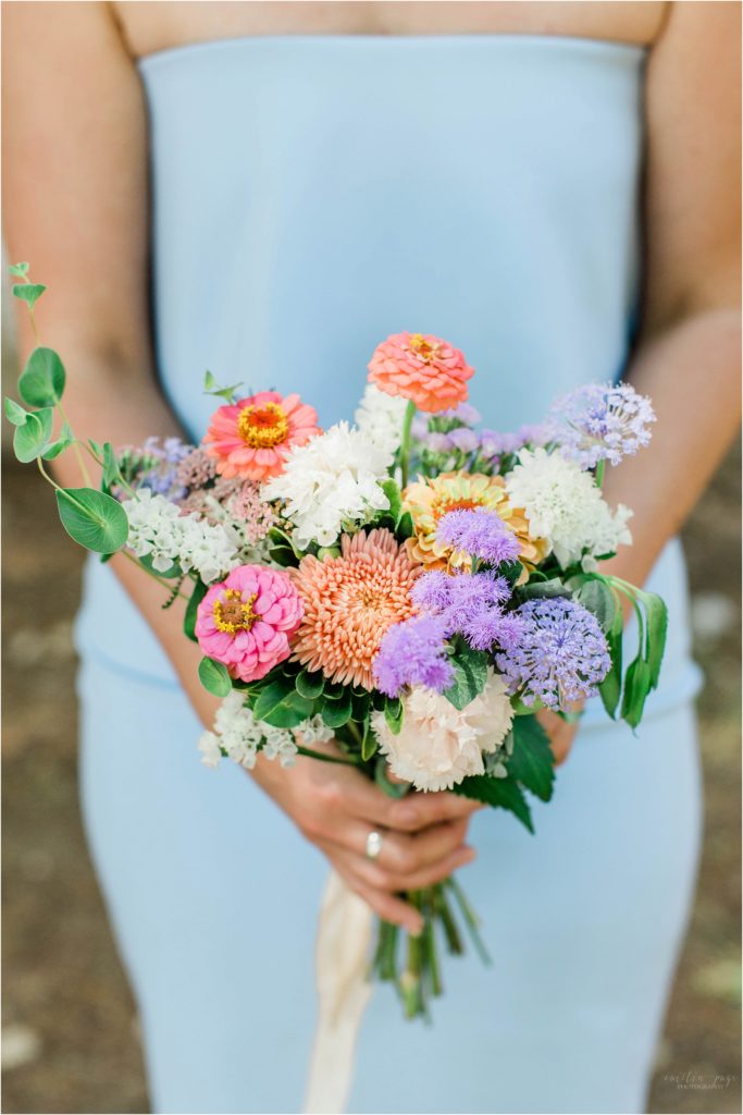 Bridesmaid in blue dress holding wildflower bouquets