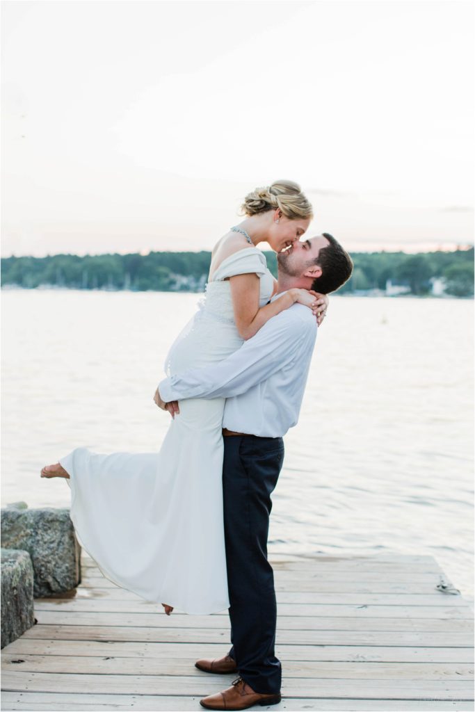 Groom holding bride on Brewster Boathouse dock