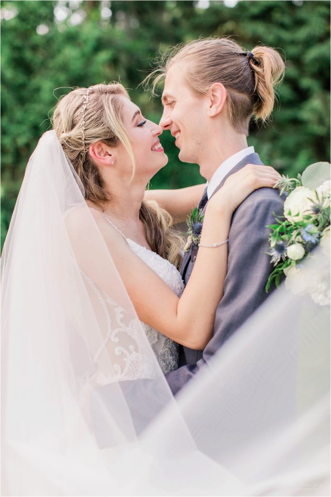 bride and groom smiling at each other with wedding veil swoop