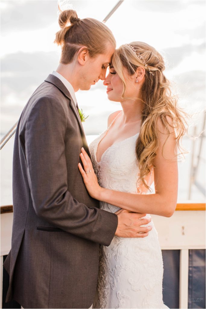 bride and groom standing on boat bow at sunset
