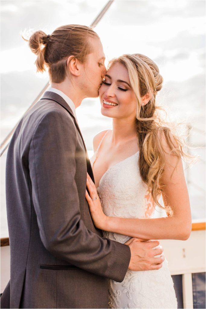 groom kissing bride on the cheek at sunset