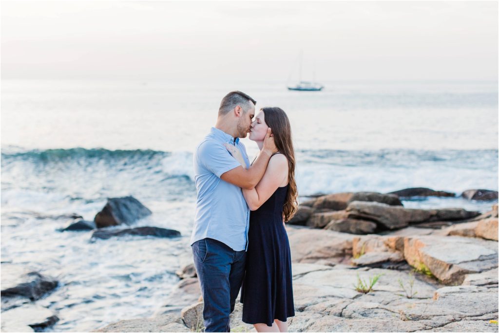 Couple kissing on rocks in front of ocean