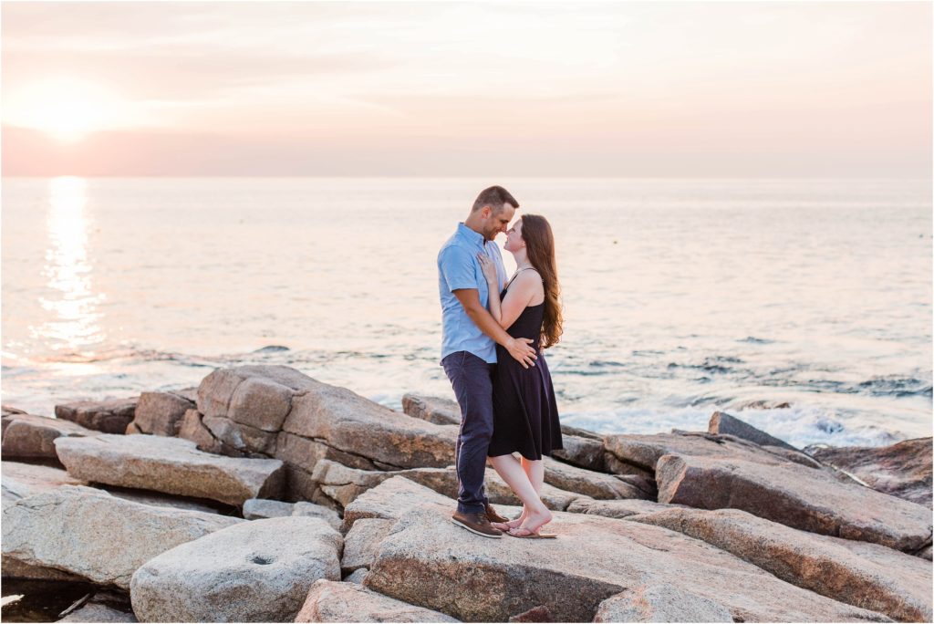 Couple standing together at sunset on rocks by ocean