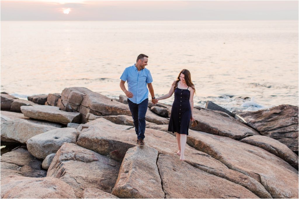 Man and woman walking together on rocks at sunset at Halibut Point State Park