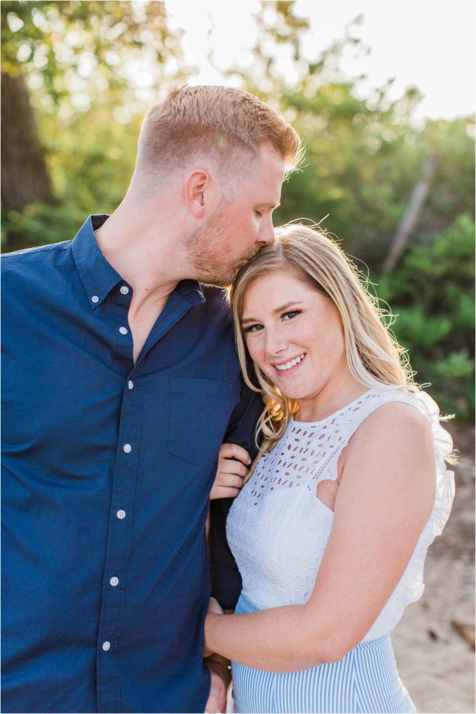 Man kissing top of woman's head at sunset