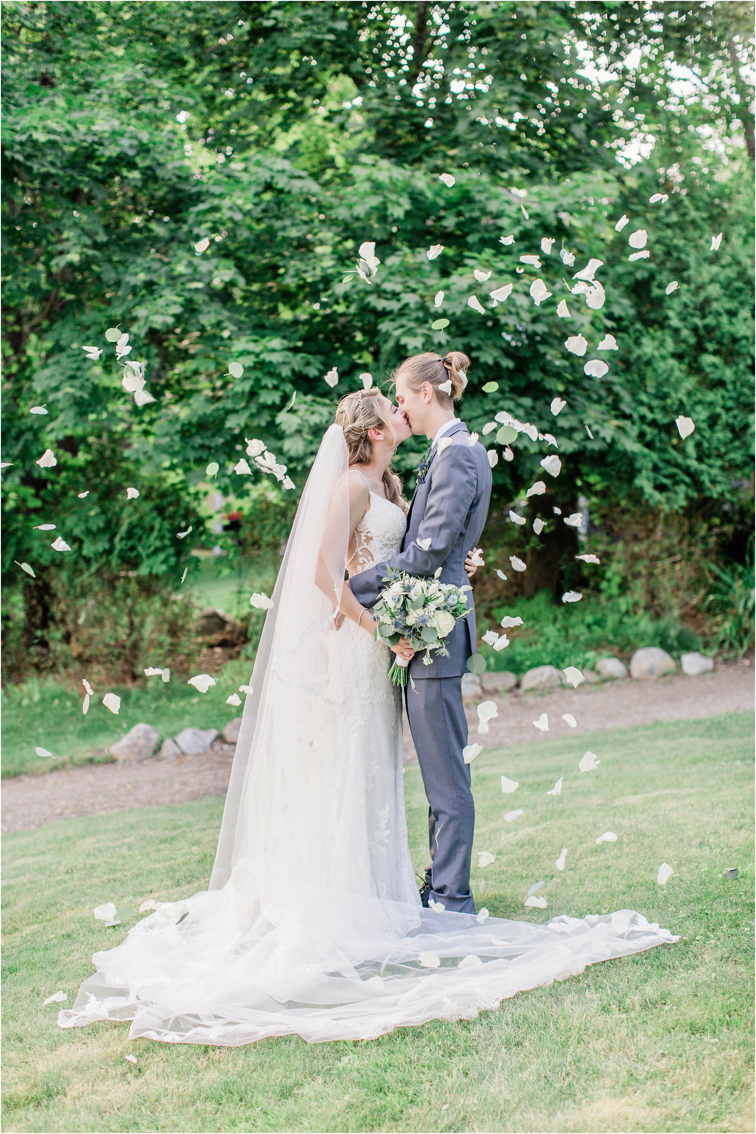 bride and groom kissing with flower petals falling around them