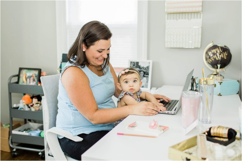 Woman and baby sitting at desk working on laptop computer