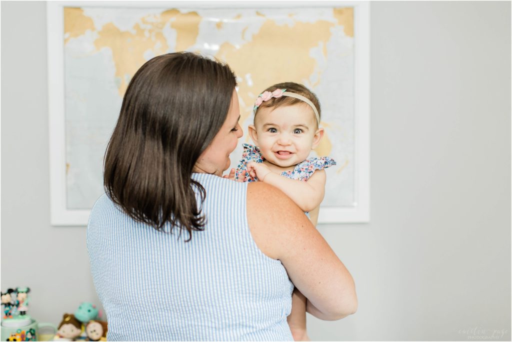 Woman holding baby in front of world map