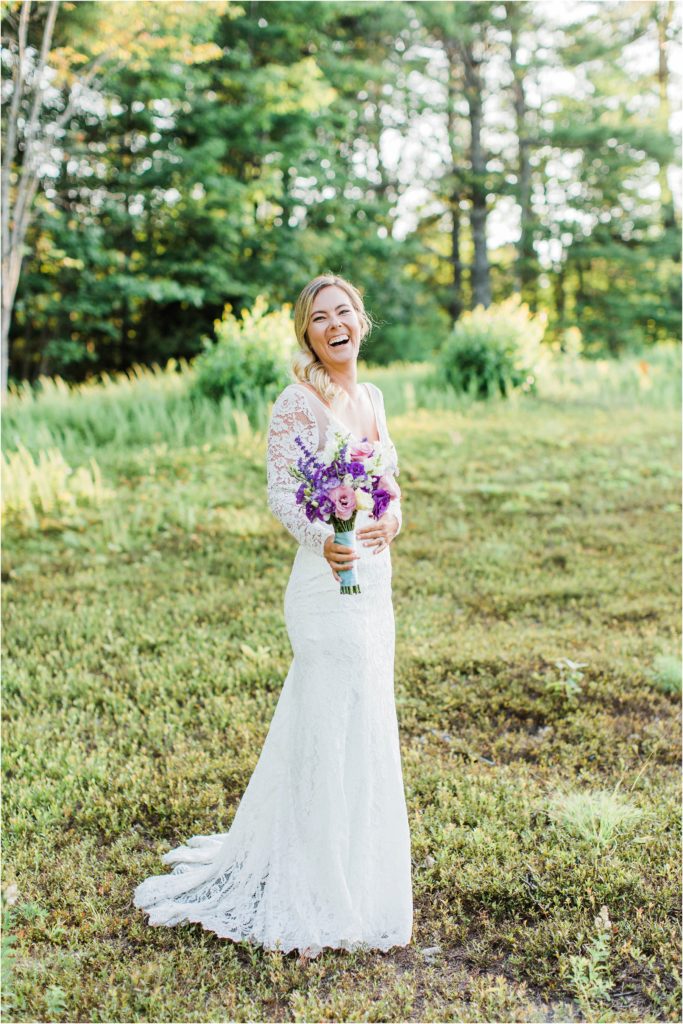 Bride standing in field with pink and purple bouquet