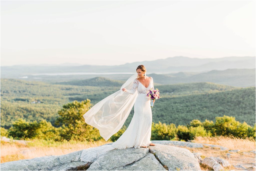 Bride standing on top of Foss Mountain at sunset with long veil and bouquet