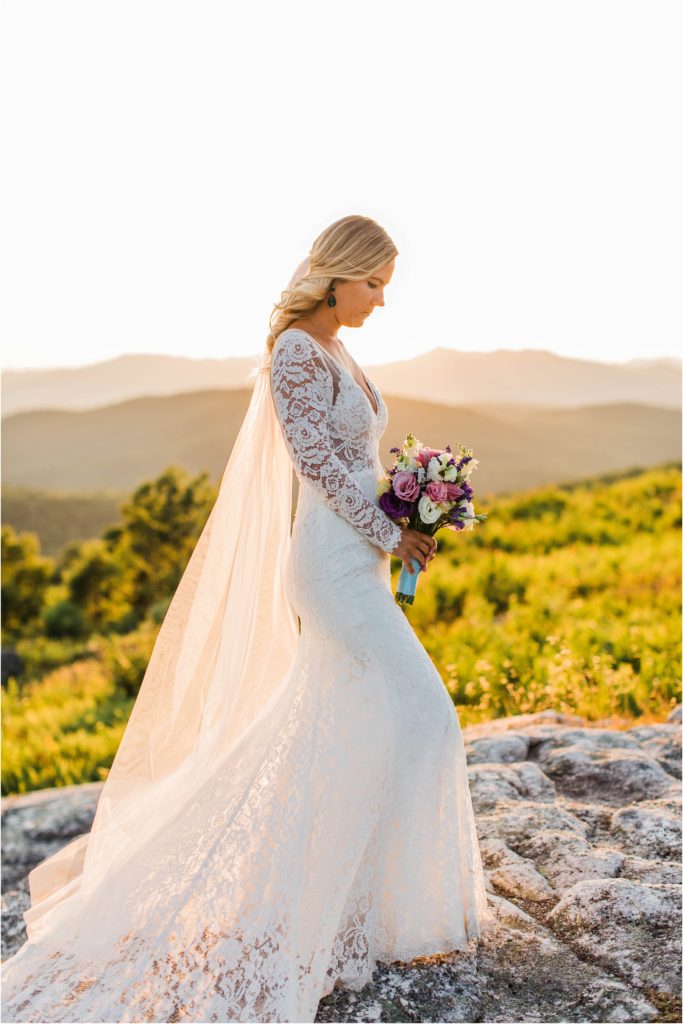 Bride standing on top of Foss Mountain at sunset with long veil and bouquet