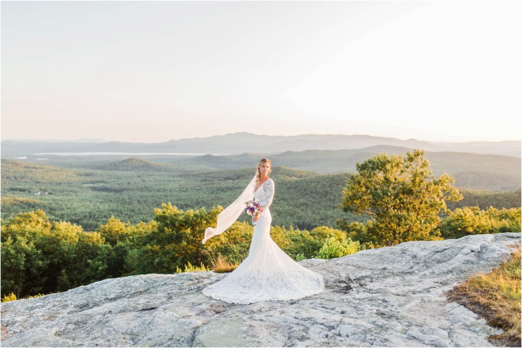 Bride standing on top of Foss Mountain with wedding bouquet and long veil