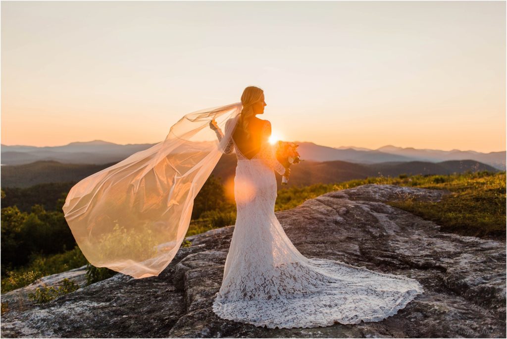 Bride standing on top of Foss Mountain at sunset with wedding bouquet and long veil
