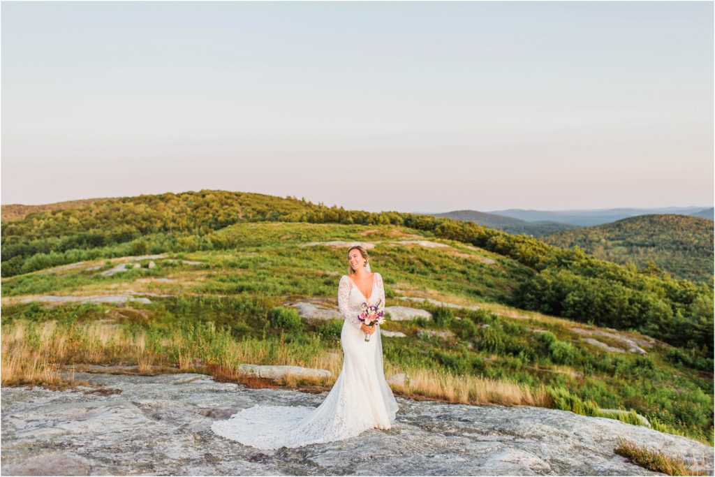Bride standing on top of Foss Mountain at sunset with wedding bouquet and long veil