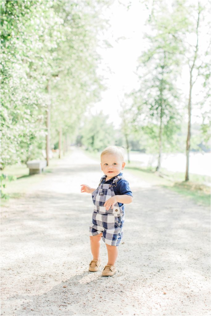 Little boy standing in middle of trail in blue checkered overalls