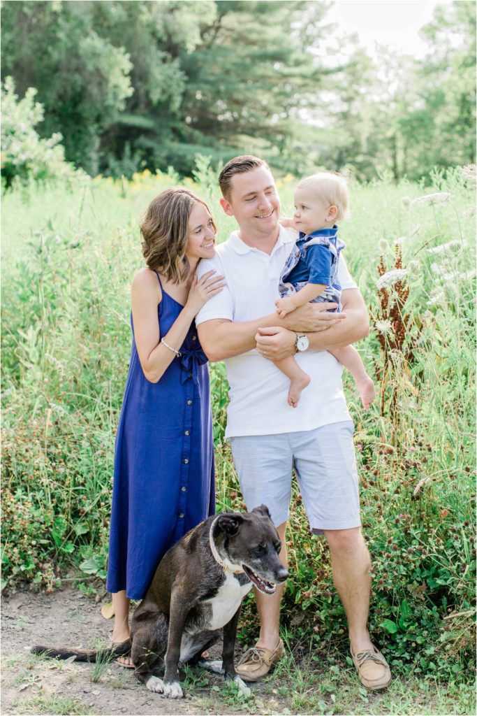 Family standing in field with baby boy and dog