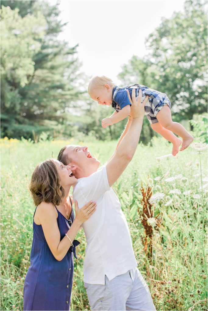 Dad holding baby boy up in the air with Mom standing behind him