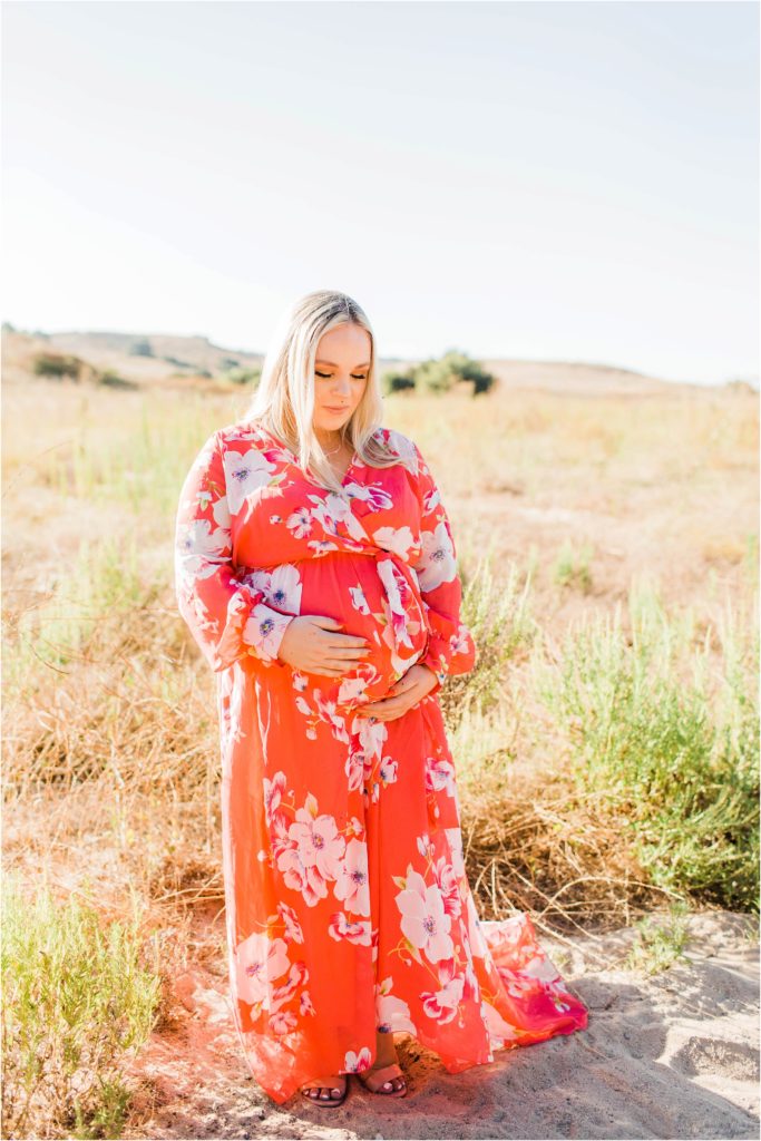 Maternity photos of woman in field in pink flowered dress