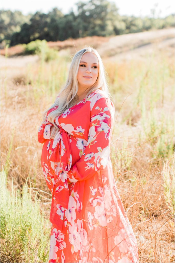 Maternity photos of woman in field in pink flowered dress