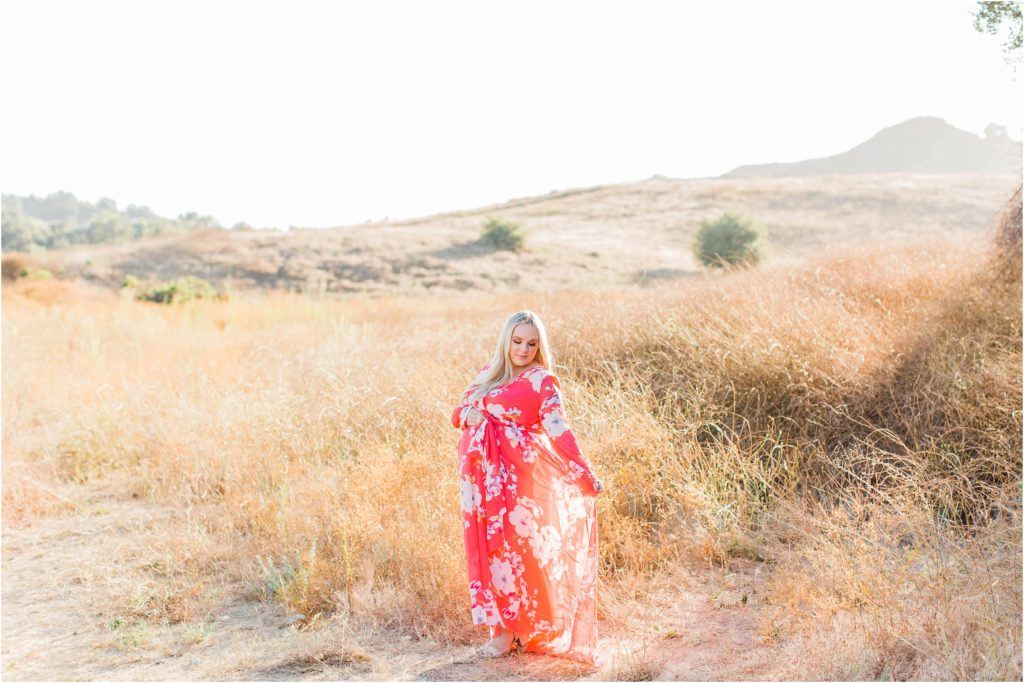 Pregnant woman standing in field with pink dress