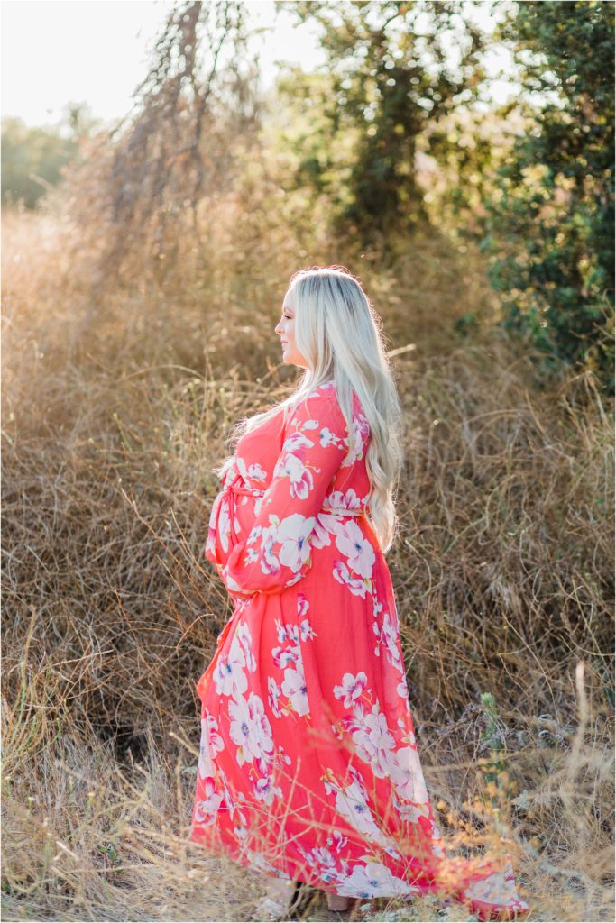 Pregnant woman standing in field under tree at sunset in Thomas Riley Wilderness Park, California