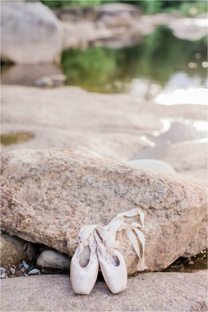 pointe ballet shoes propped against rock
