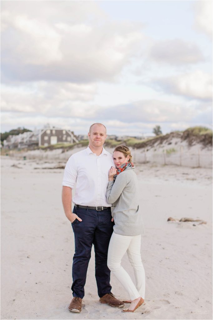 couple standing together on beach with dunes behind