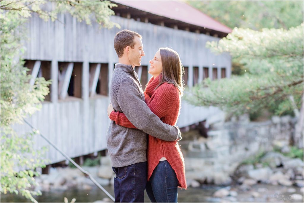 couple standing in front of covered bridge at sunset