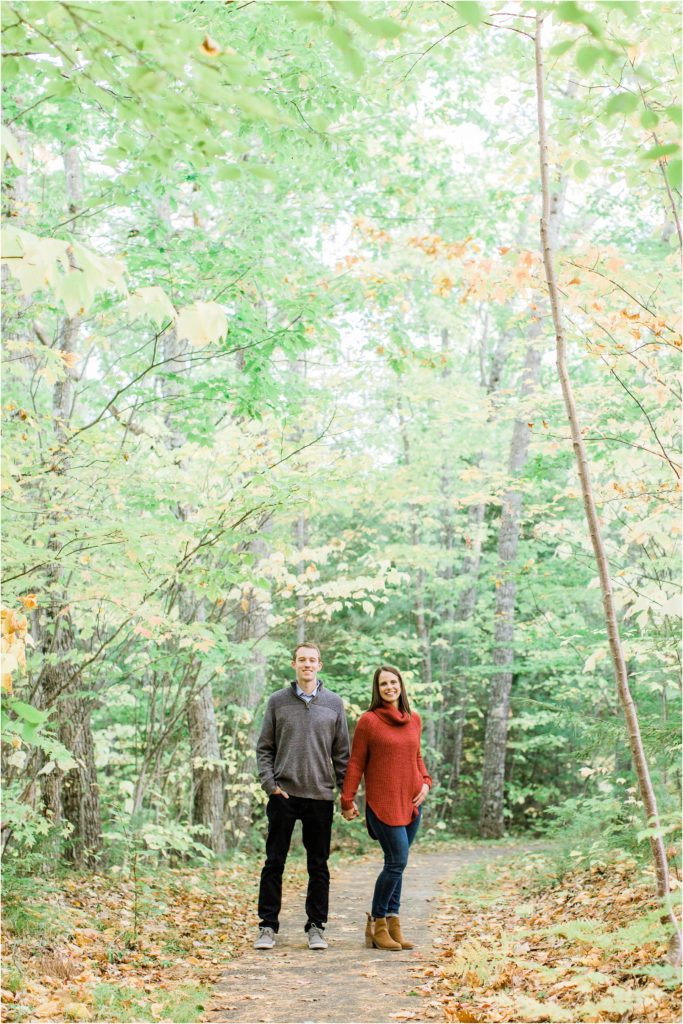 couple standing on trail in middle of woods