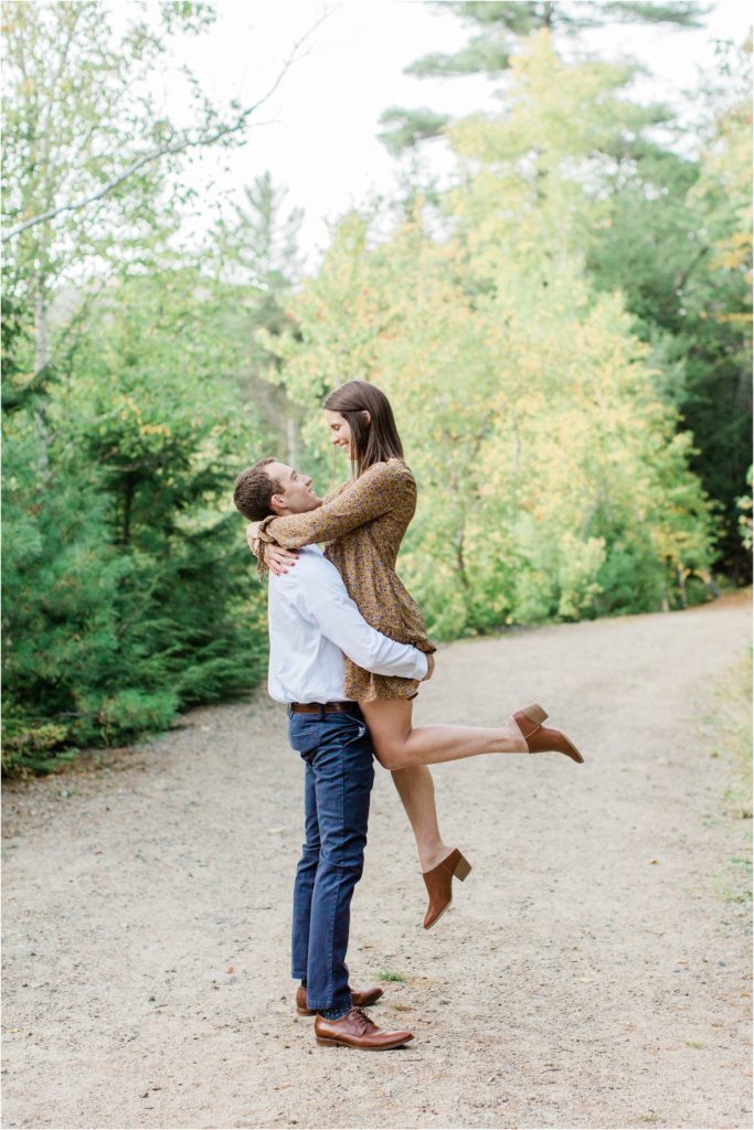 man holding woman in the air engagement photos