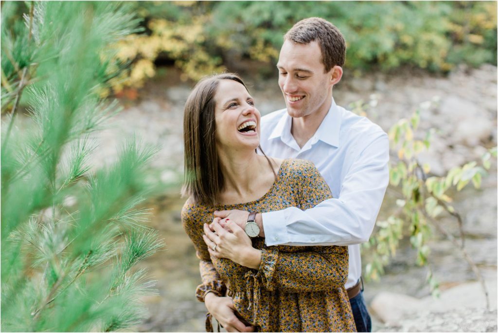 man snuggling woman by river