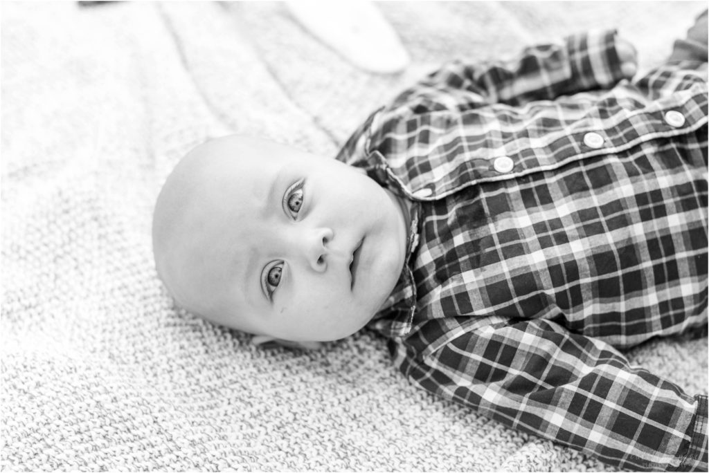 Black and white photo of baby boy laying on blanket