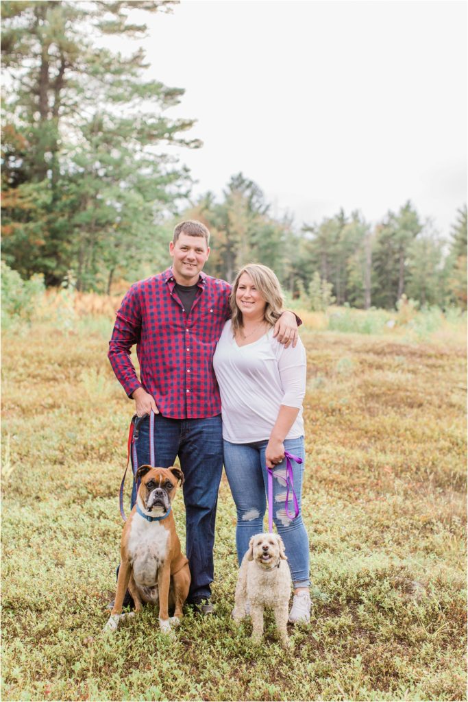 man and woman standing in field with dogs