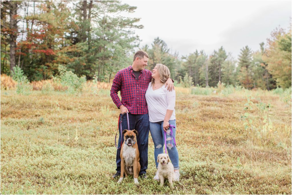 man and woman standing in field with dogs