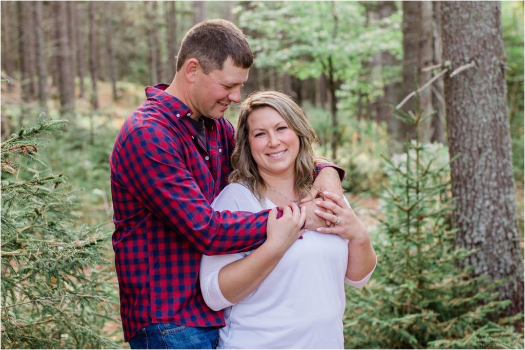 man and woman snuggled in the woods