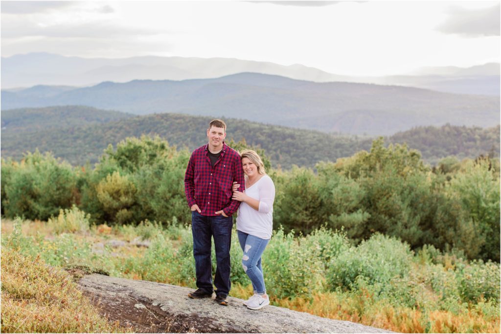 man and woman standing together on mountain top at sunset