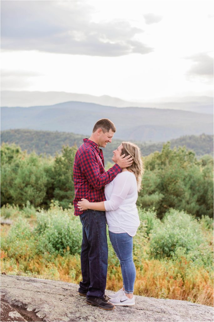 man and woman standing together on mountain top at sunset