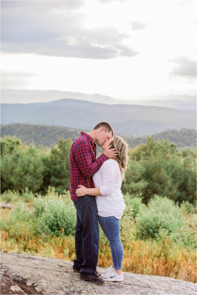 man and woman standing together on mountain top at sunset