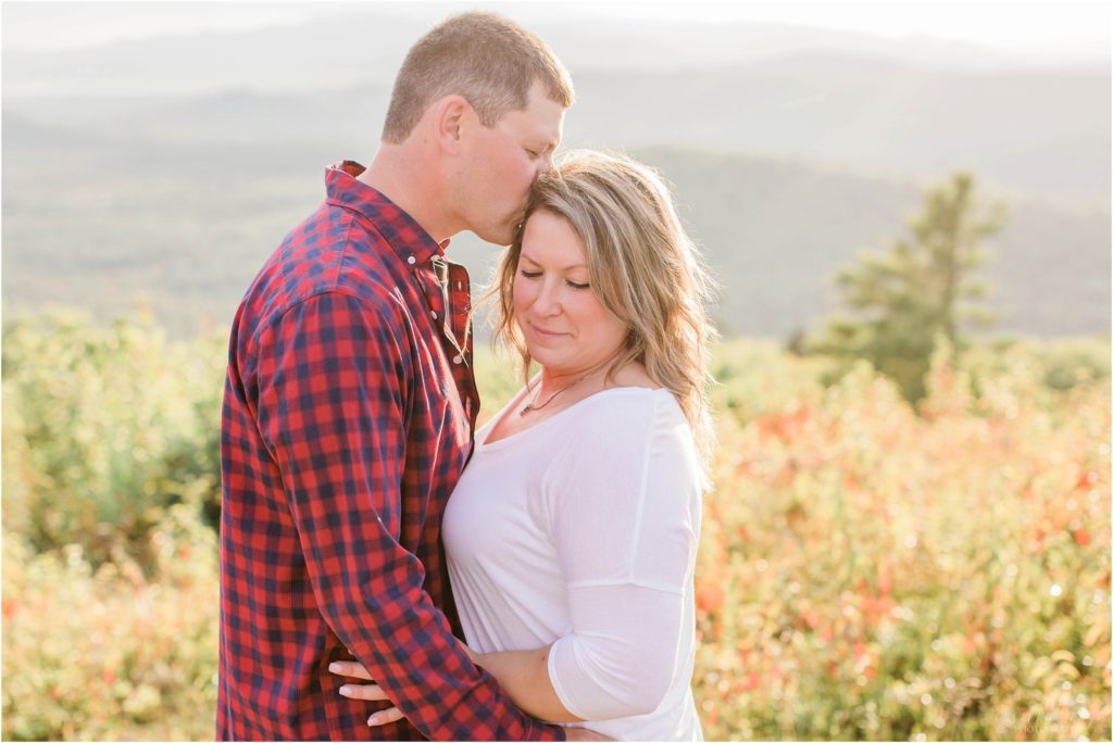 man and woman snuggled together on mountaintop at sunset