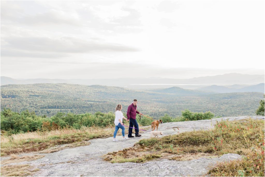 man and woman walking with dogs on mountain top