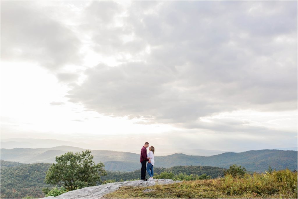 man and woman standing together on mountain top at sunset