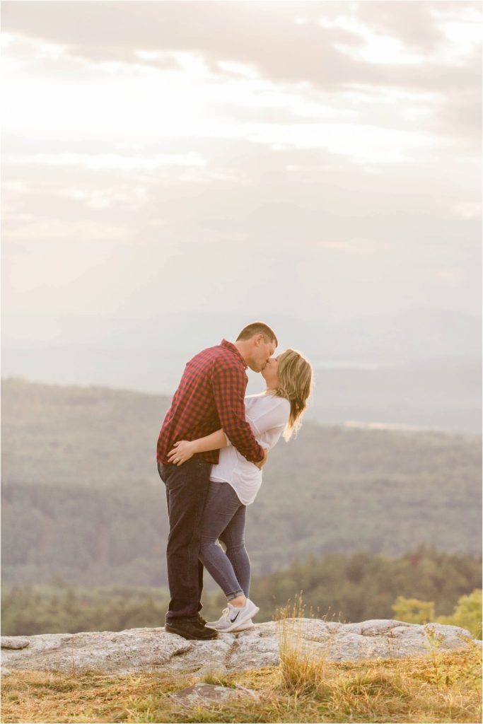 man dipping woman backwards on mountaintop at sunset