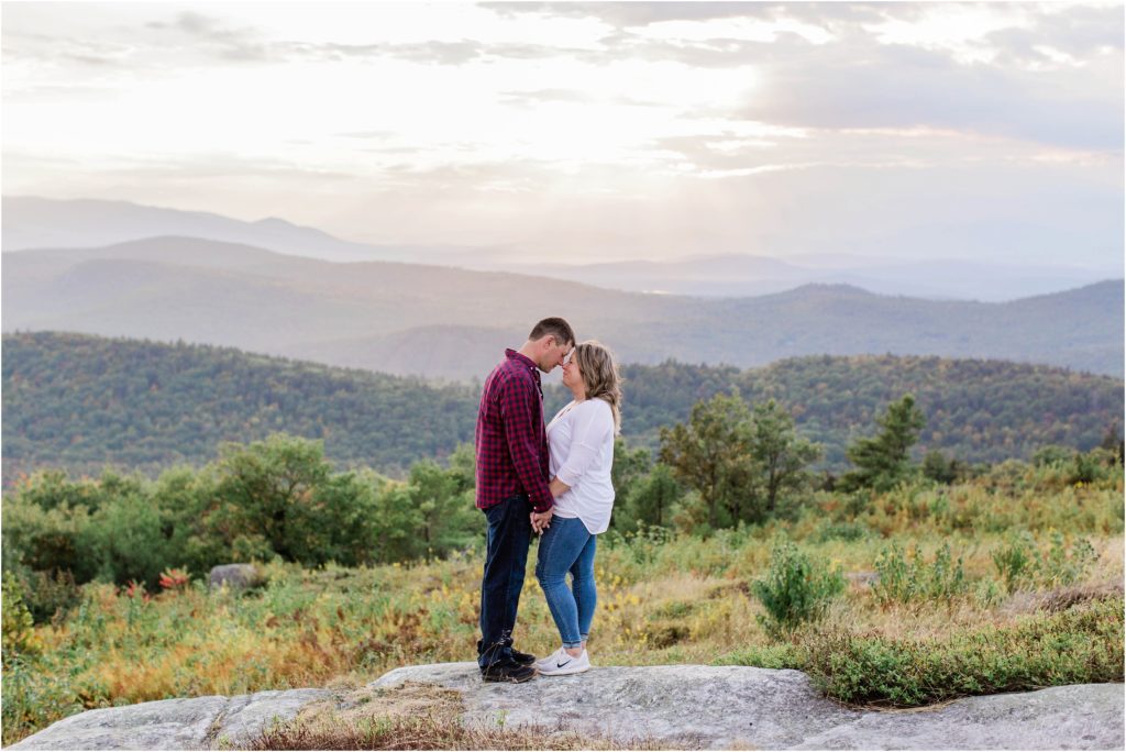 man and woman standing together on mountain top at sunset