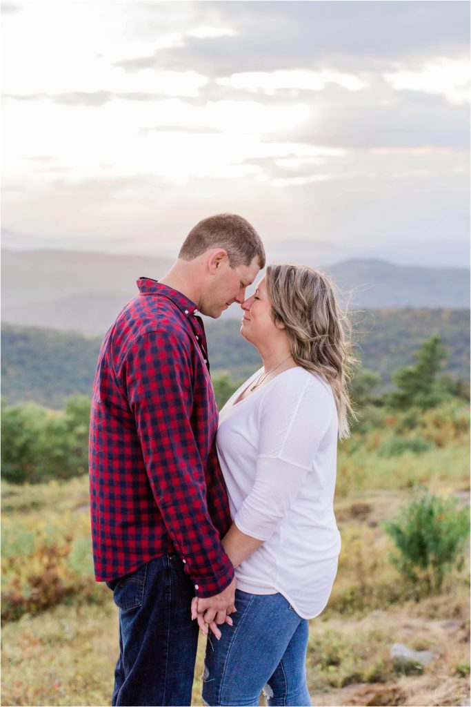 man and woman standing together on mountain top at sunset