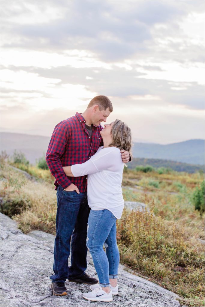 man and woman standing together on mountain top at sunset