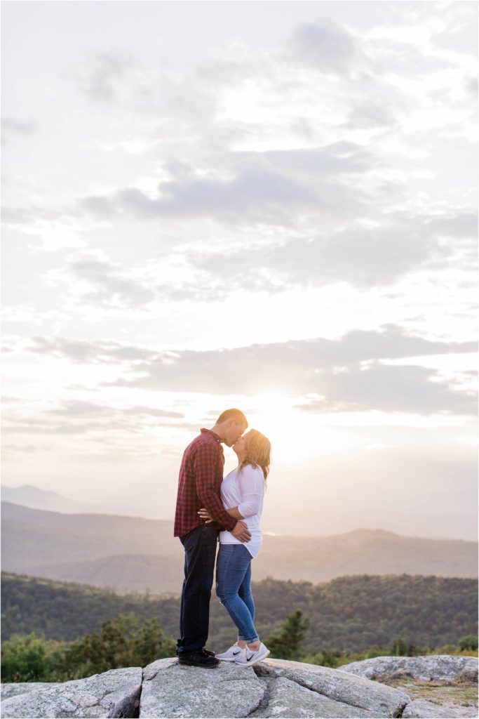 man and woman standing together on mountain top at sunset