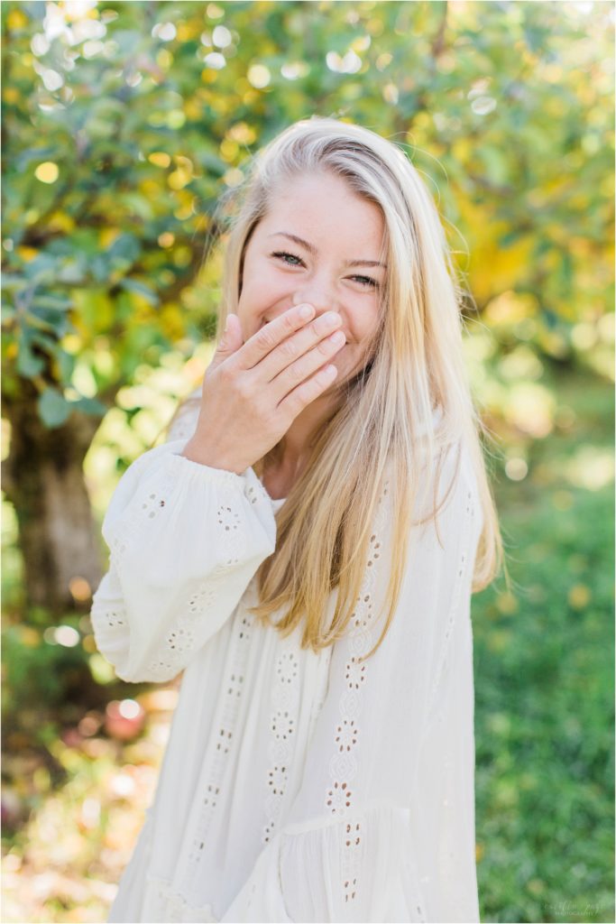 Senior girl laughing in apple orchard